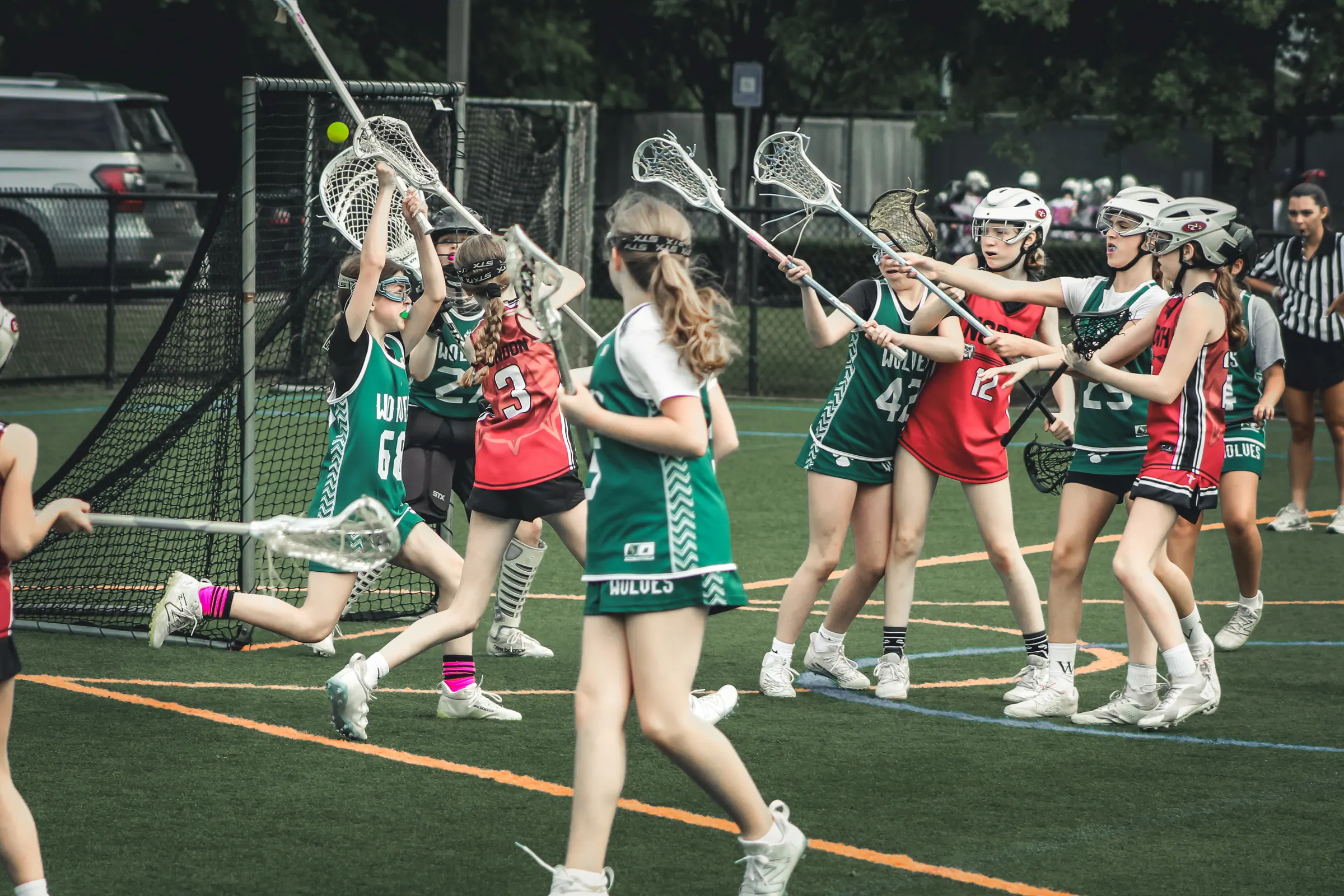 Girls lacrosse players competing near the goal